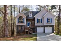 Charming two-story home with stone accents, blue shutters, and attached two-car garage at 6490 Lake Esther Dr, Fairburn, GA 30213