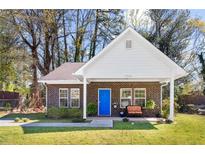 Charming brick home with a bright blue door and cozy front porch seating area at 3706 Clovis Nw Ct, Atlanta, GA 30331