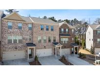 View of townhomes with brick facade, garages, and professionally landscaped front yards at 3567 Hidden Valley Cir, Lawrenceville, GA 30044