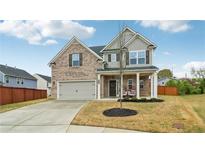 Inviting two-story home featuring a brick facade, attached garage, and covered front porch with swing at 4443 Quilter St, Powder Springs, GA 30127