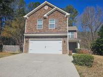 Two-story home with a stone facade, attached garage and driveway on a sunny day at 100 Iverson Pl, Temple, GA 30179