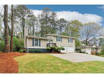 Inviting two-story home featuring a manicured lawn, a two-car garage, and mature trees offering ample shade at 746 Polk Nw St, Marietta, GA 30064