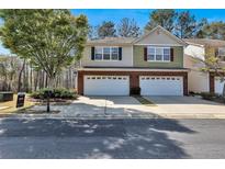 Two-story townhome with a two-car garage, brick accents, and a well-maintained front yard under a blue sky at 1080 Treymont Ln, Lawrenceville, GA 30045