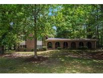 Charming brick home featuring an arched front porch and a lush, green, tree-filled front yard at 2544 Peyton Woods Sw Trl, Atlanta, GA 30311