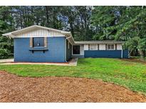 Charming home featuring a blue brick exterior, well-maintained lawn, and mature trees offering shade and curb appeal at 4756 Fellsridge Dr, Stone Mountain, GA 30083