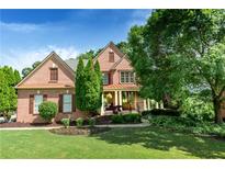 Charming two-story brick home with lush landscaping, mature trees, and a welcoming front porch at 5347 Harbury Cv, Suwanee, GA 30024