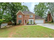 Charming two-story brick home with mature trees and a well-manicured lawn on a cloudy day at 5611 Manassas Run, Stone Mountain, GA 30087