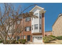 Charming two-story townhome featuring a brick facade, attached garage, and manicured landscaping under a clear blue sky at 2164 Mill Garden Run, Buford, GA 30519