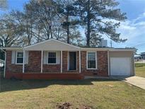 Charming brick home with front porch and attached one-car garage on a sunny day at 407 Hilltop Dr, Forest Park, GA 30297