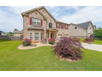 Charming brick home with a well-manicured lawn, beautiful flower beds, and a two-car garage at 8097 White Oak Loop, Lithonia, GA 30038