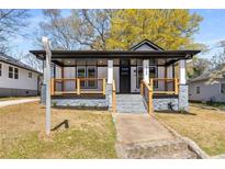 Charming home featuring a covered front porch with stone accents and freshly landscaped yard at 1569 Montreat Sw Ave, Atlanta, GA 30311