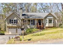 Charming split-level home featuring a two-car garage, inviting front porch, and manicured lawn at 877 Old Farm Walk, Marietta, GA 30066