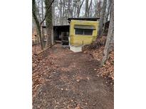 Exterior view of a single wide mobile home nestled among trees in a rustic setting at 1000 Delta A15, Canton, GA 30114