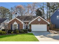 Charming brick home with a two-car garage, manicured lawn, and beautiful landscaping in a residential neighborhood at 2324 Leacroft Way, Marietta, GA 30062