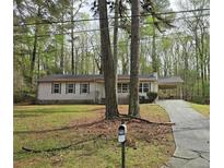 Charming single-story home with a covered carport and an asphalt driveway nestled among mature trees at 7508 Asbury Manor Dr, Lithonia, GA 30058