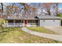 Charming gray home with a welcoming front porch, red door, and manicured lawn offers great curb appeal at 1354 Litchfield Ct, Snellville, GA 30078