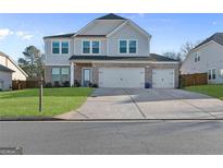 Charming two-story home featuring a gray exterior, brick accents, an attached three-car garage, and a well-manicured lawn at 3560 Summerpoint Xing, Cumming, GA 30028