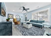 Bright living room with a modern blue sofa, stylish rug, and plenty of natural light from the large window at 2535 Judson Ave, East Point, GA 30344