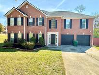 Charming two-story brick home featuring a well-manicured lawn and attached two-car garage at 4244 Old House Dr, Conley, GA 30288