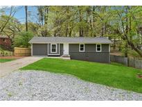 Charming single-story home with a gray exterior, fresh green lawn, and a gravel driveway at 2115 Randolph Nw Cir, Kennesaw, GA 30144