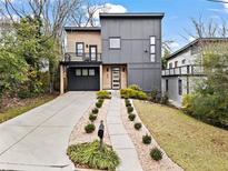 Modern two-story home with a gray facade, wood accents, balcony, a front yard with a walkway and manicured landscaping at 1560 New Ne St, Atlanta, GA 30307