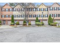 View of the townhomes showing multiple units with individual garages and neatly maintained landscaping at 1506 Knights Trl, Stone Mountain, GA 30083