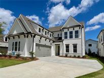 Beautifully landscaped two-story home featuring painted brick and concrete driveway under a cloudy blue sky at 486 Broom Dr, Cumming, GA 30040