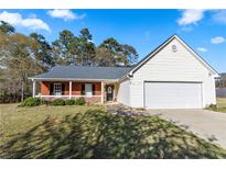 Charming single-story home with brick accents, a covered porch, and a two-car garage at 704 Manor Ridge Dr, Loganville, GA 30052