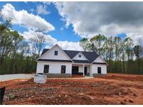 New construction shows an inviting white farmhouse-style home with a dark roof and black trim amid a wooded landscape at 490 Benson Meadows Dr, Dallas, GA 30157