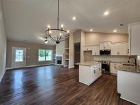 Open-concept living room with dark wood floors, stone fireplace, and gourmet kitchen with island at 476 Benson Meadows Dr, Dallas, GA 30157