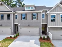 Modern townhome with a gray brick facade, complemented by a neutral gray garage door and manicured landscaping at 1387 Fern Ridge Ct # 33, Norcross, GA 30093