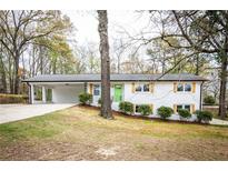 Charming single-story home with a brick facade, bright green front door, and attached carport in a wooded setting at 3888 W Oak Dr, Douglasville, GA 30135