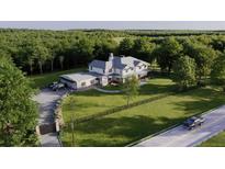 Stunning aerial view of a white farmhouse-style home with long driveway and lush green surroundings at 4385 Hickory Flat Hwy, Canton, GA 30115