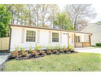 Charming one-story home with a well-manicured lawn, fresh flowers, and natural wood porch accents at 716 Sunfield Nw Dr, Lilburn, GA 30047