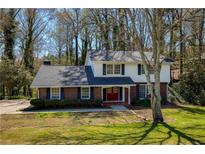 Charming two-story home with brick facade, a well-manicured lawn, mature trees and dark shutters at 520 Willeo Rd, Roswell, GA 30075