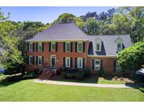Beautiful two-story brick home with green shutters and a well-manicured lawn and mature trees at 5162 Charlemagne Sw Way, Lilburn, GA 30047