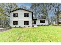 Beautifully renovated two-story home with a freshly painted white brick and siding exterior and manicured lawn at 1450 Cedarhurst Dr, Dunwoody, GA 30338