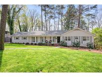 Charming single-story home with a manicured lawn, brick facade, and inviting front porch at 1254 Moores Mill Nw Rd, Atlanta, GA 30327