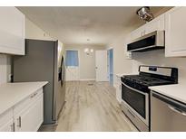 Modern kitchen featuring stainless steel appliances, white cabinets and countertops, and new flooring at 908 Kennesaw Dr, Forest Park, GA 30297