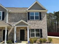 Charming townhome featuring a brick facade, black shutters, and well-maintained landscaping at 6420 Olmadison Pl, Atlanta, GA 30349