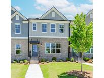 Charming brick townhome featuring gray accents, a well-manicured lawn, and inviting walkway, all under a bright blue sky at 1260 Ainsworth Aly # 47, Sugar Hill, GA 30518