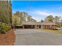 Charming brick ranch home featuring a spacious driveway and inviting front porch, perfect for relaxing outdoors at 2520 Robin Hood Ne Pl, Marietta, GA 30068