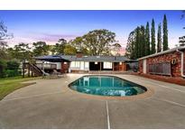 Beautiful backyard pool with deck, lounge chairs, and landscaped yard with tall trees at 2520 Robin Hood Ne Pl, Marietta, GA 30068