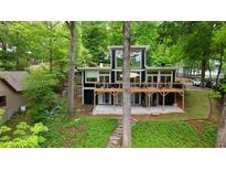 Contemporary two-story home with large windows and spacious deck surrounded by lush greenery and mature trees at 132 Lakeshore Dr, Roswell, GA 30075