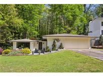Charming ranch-style home with a two-car garage, beautiful landscaping, and a well-manicured lawn at 240 W Spalding Dr, Sandy Springs, GA 30328