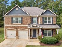 Two-story brick home with a two-car garage, covered porch, and manicured landscaping at 346 M J Mccarthy Way, Hampton, GA 30228