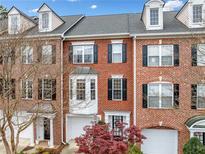 Charming brick townhome featuring a bay window, dormers, black shutters, and a two-car garage at 4908 Waters Edge Trl, Roswell, GA 30075