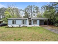 Charming light blue one-story home with well-manicured lawn and covered carport at 1601 Sycamore Nw Dr, Kennesaw, GA 30152