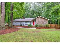 Charming single-story home with a stone accent wall, red front door, mature trees, and a well-maintained lawn at 346 Buckingham Sw Dr, Conyers, GA 30094