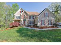 Charming home featuring stone accents, a red front door, mature landscaping, and a green lawn at 241 Rose Ridge Dr, Canton, GA 30115